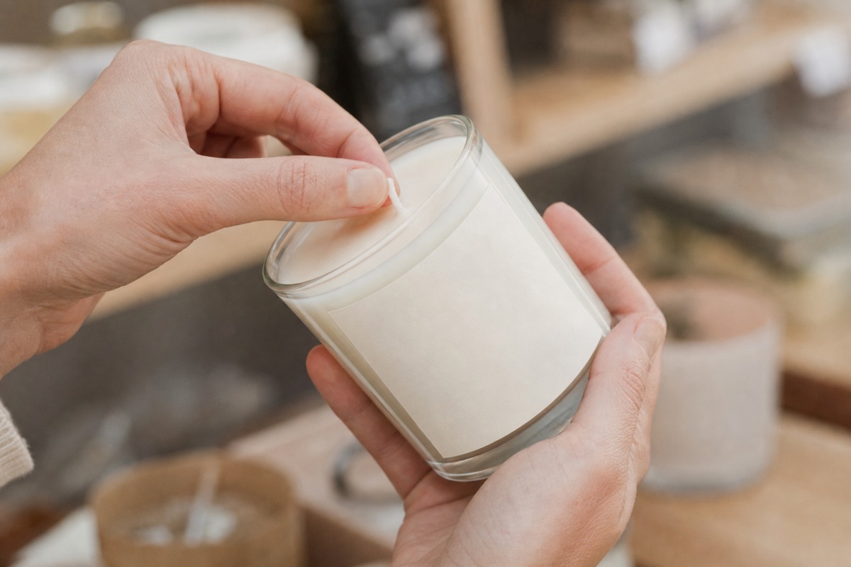 Mani che controllano lo stoppino di cotone e l'etichetta scarna di una candela prima dell'acquisto in negozio