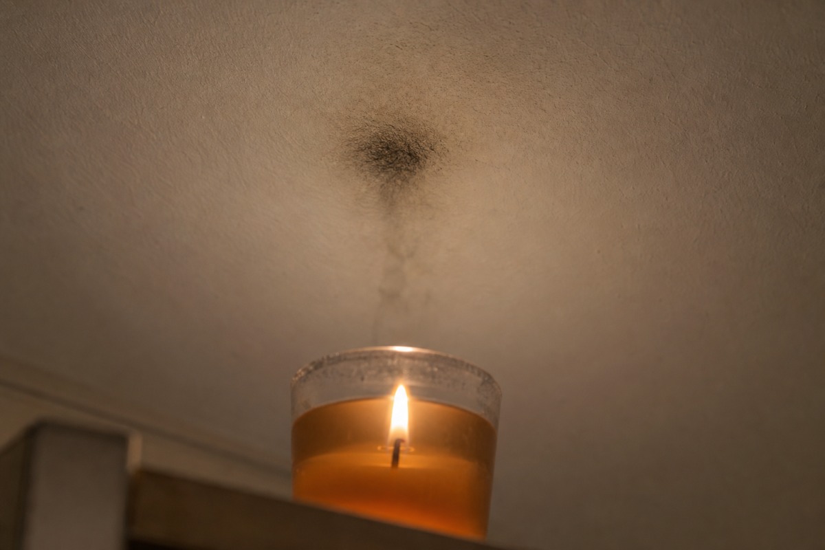 Traccia scura di fuliggine sul soffitto bianco, proprio sopra una candela al gel accesa in un bicchiere di vetro